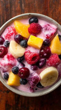A Bowl Of Fruit Salad With Yogurt Topped With Berries And A Banana Slice — Stock Photo