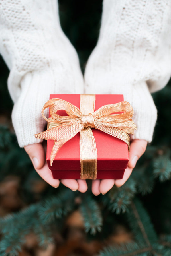 A Person Holding A Red Gift Box With A Bow Set Against A Festive Holiday Background — Stock Photo
