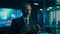 businessman in suit standing in office with hands clasped together gesturing with right hand while speaking to someone off camera - Stock Video