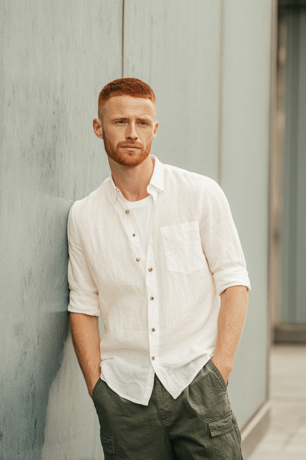 Man With Red Hair Leaning Against A Wall Wearing A White Shirt And Dark Pants — Stock Photo
