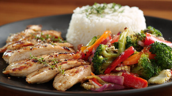 Three Plates Of Chicken And Vegetables On A Black Plate Against A Wooden Table — Stock Photo