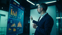 a man in a suit gesturing towards a large screen various charts and graphs - Stock Video
