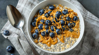 Bowl Of Oatmeal Topped With Blueberries And Drizzled With Honey On A Wooden Table — Stock Photo