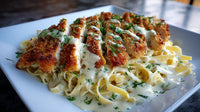 A Plate Of Chicken Parmesan Covered In Alfredo Sauce Garnished With Herbs And Served On A White Dish — Stock Photo