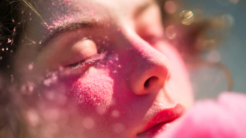 woman with pink powder on face in close up with soft lighting and a blurred background - Stock Video