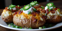 Close Up Of Four Loaded Baked Potatoes On A White Plate Garnished With Sour Cream And Chives Served In A Restaurant Setting — Stock Photo