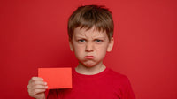A Young Boy Holding A Red Card In Front Of Him Against A Red Background — Stock Photo