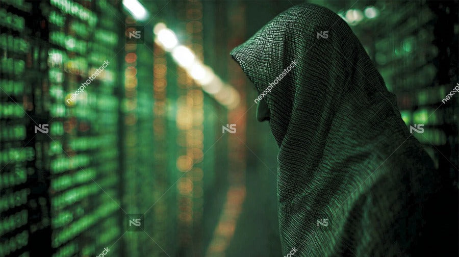 A Person Wearing A Hooded Cloak And Mask Stands Amidst Rows Of Computer Servers In A Data Center Surrounded By Green Lights — Stock Photo