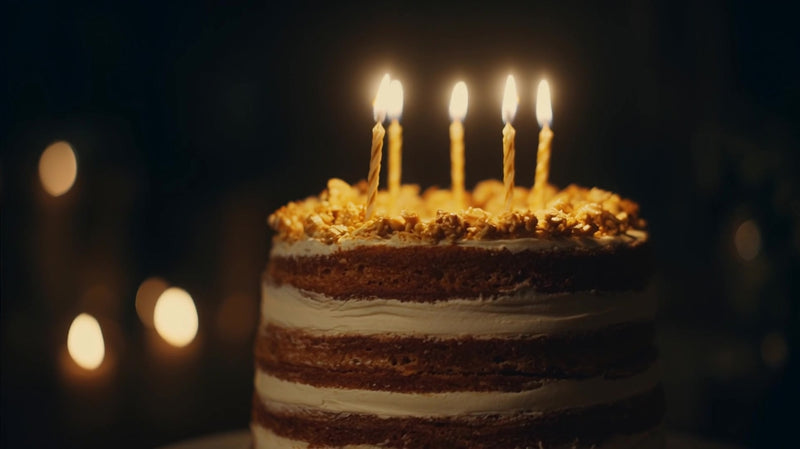 a birthday cake with lit candles topped with gold foil and a chocolate frosting - Stock Video