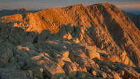 a sunset over a rocky mountain range with the sky transitioning from warm hues to cooler tones as it meets the horizon - Stock Video