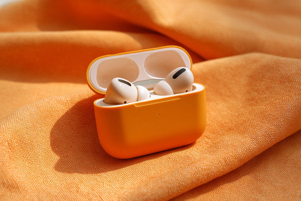 Shows A Small Orange Container With Two White Earbuds Inside It Placed On A Fabric Surface That To Be A Tablecloth Cloth — Stock Photo