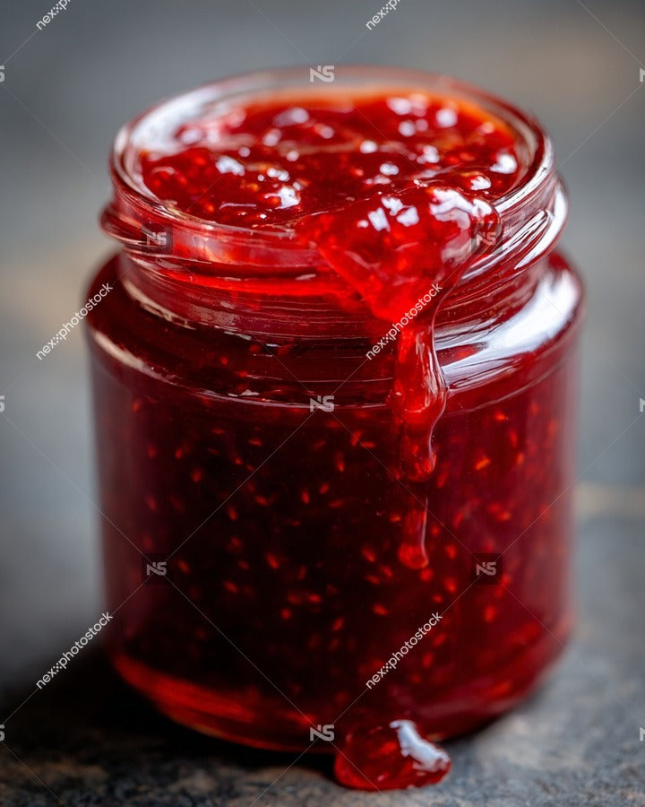 A Jar Of Raspberry Jam With A Spoonful Of Jam Spilling Out Onto A Surface — Stock Photo