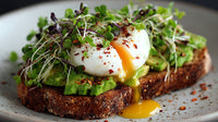 A Plate Of Avocado Toast Topped With Fried Eggs And Sprinkled With Herbs Served On A Wooden Table — Stock Photo