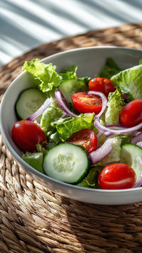 A Bowl Of Salad With Cucumbers Tomatoes And Lettuce On A Table — Stock Photo