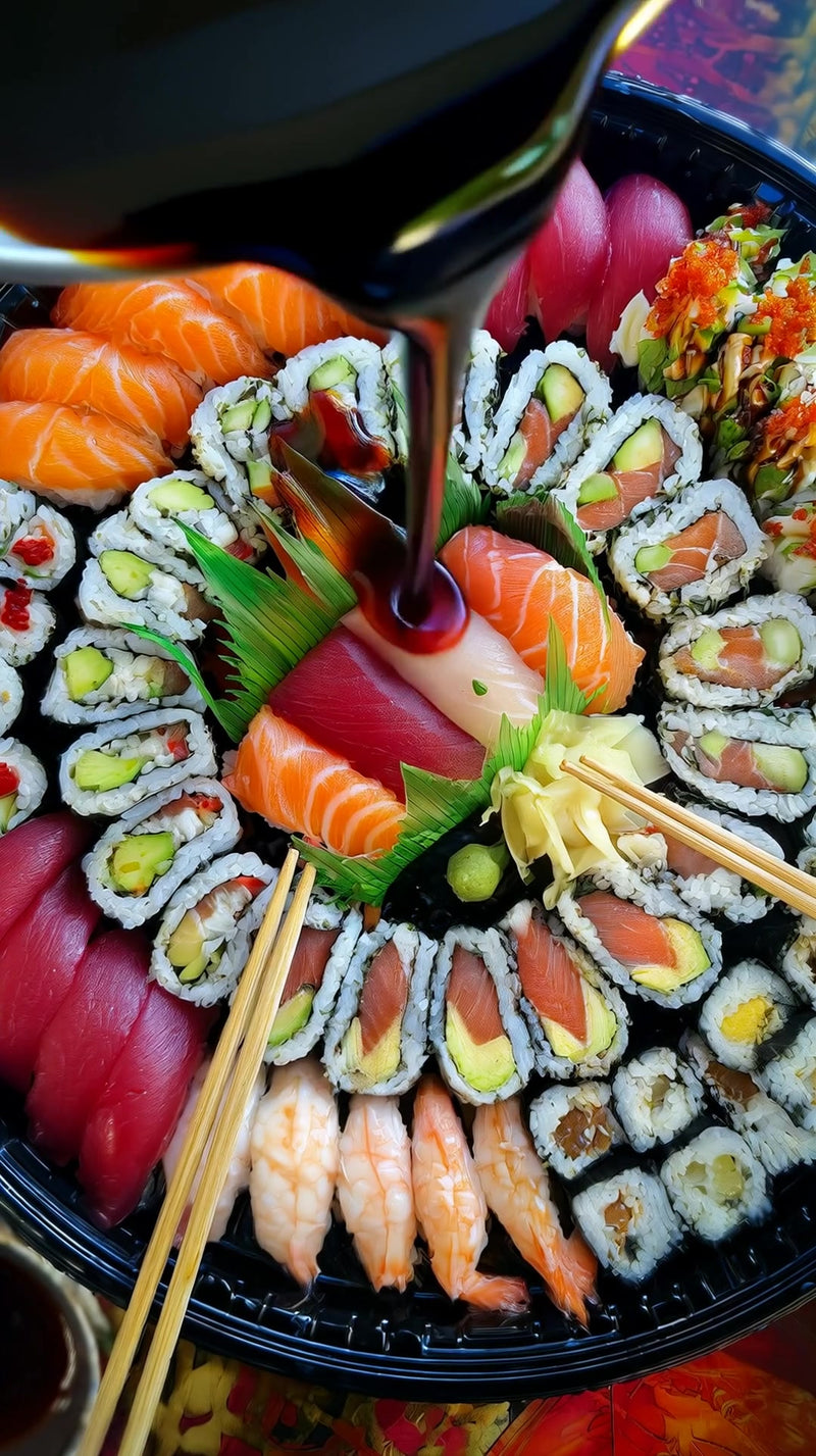 a variety of sushi rolls displayed in a black tray including salmon tuna and vegetable options arranged on a dining table - Stock Video
