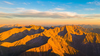 majestic mountain range bathed in warm hues of sunset with a clear sky and scattered clouds above - Stock Video